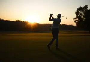 A golfer on a beautiful golf course practicing a swing at sunset.