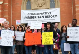 Diverse group supporting immigrant rights with signs outside a church